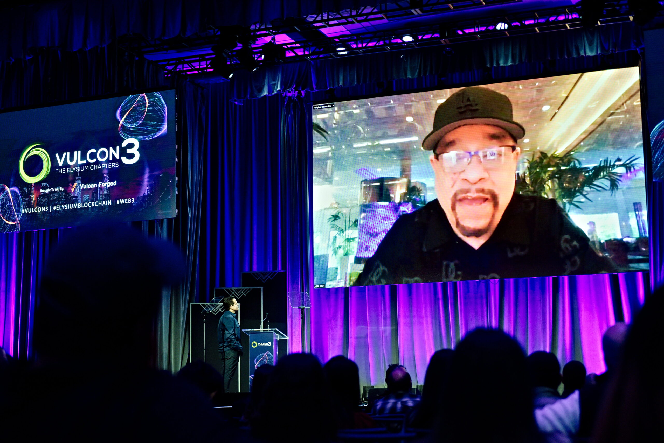Ice-T on screen at Vulcan Forged's VulCon3 talking to Anthony Scaramucci at Ziegfeld Ballroom, New York City, May 2023.